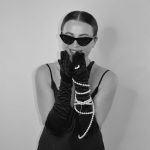 A stylish woman wearing sunglasses, opera gloves, and pearls, exuding classic elegance.